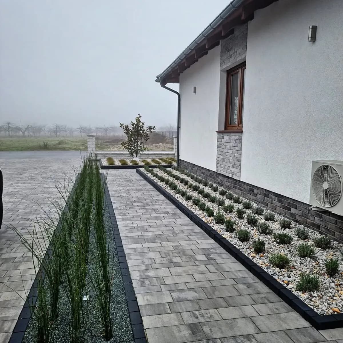 Chodnik z płyt wzdłuż domu z obsadzoną rabatą
